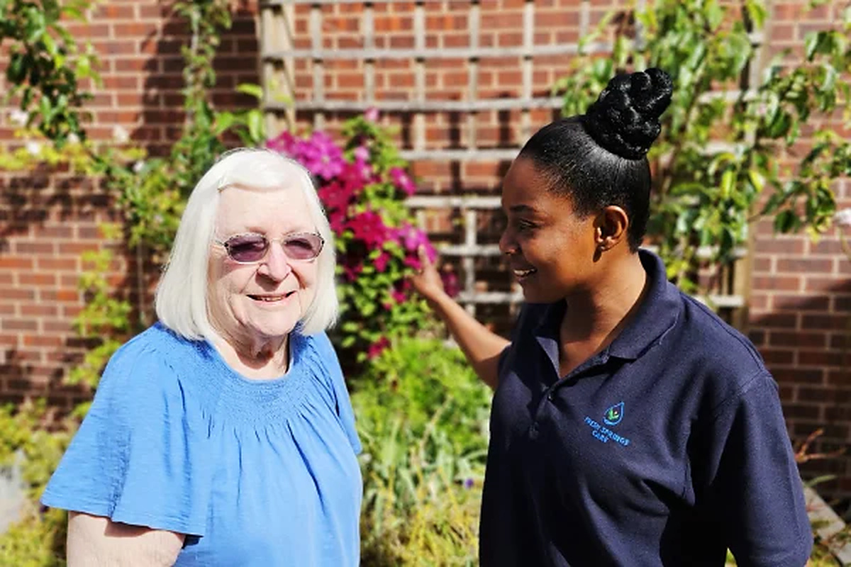 Fresh Springs Care carer standing outdoors with an elderly woman in a garden in Bristol