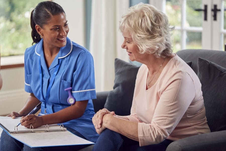 Real Client Experiences with Fresh Springs Care Services in Highworth Smiling home care worker chatting with an elderly client on the sofa at home in Highworth
